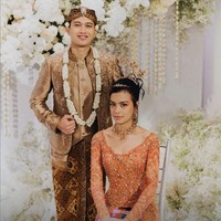 Dekorasi putih tampak kontras dengan busana Eva Celia dan Demas Narawangsa yang merupakan perpaduan oranye, emas dan cokelat. Keindahan dekorasi pernikahan merupakan karya dari Yu Cien Lotus Design. Foto: Instagram/@thebridestory & @terralogical