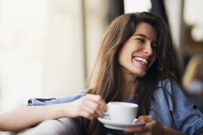 Beautiful young Caucasian ethnicity woman sitting at the cafe, relaxing and enjoying a cup of coffee.