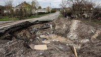Sebuah kawah bekas hantaman rudal memutus akses jalan di Desa Yatskivka, Ukraina timur. (AFP/Ronaldo Schemidt).