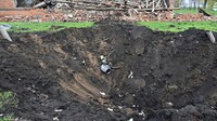 Roket tertancap di tanah yang membentuk kawah di wilayah Kharkiv, Ukraina. (AFP/Sergey Bobok).