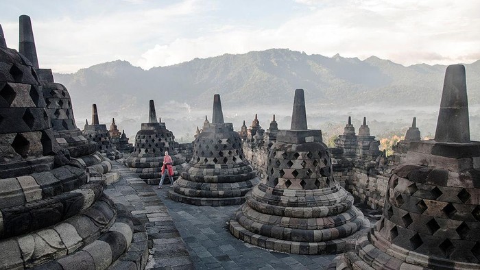 BOROBUDUR, SPECIAL REGION OF YOGYAKARTA, CE, INDONESIA - 2015/04/20: A tourist walks on the top platform of the Borobudur temple. The temple, built in the 8th century, is one of the largest Buddhist monuments in the world. Probably due to the decline of Buddhism and the Javanese conversion to Islam, it was abandoned for centuries and covered with volcanic ashes and thick vegetation. The UNESCO inscribed the temple on its world heritage list in 1991. (Photo by Thierry Falise/LightRocket via Getty Images)