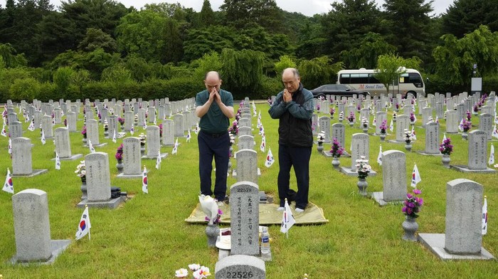 Potret Korea Selatan Peringati Pahlawan yang Gugur South Korean Choe Geun-ho and Choe In-suck, left, pray in front of the gravestone of their uncle Choe Hyun-jun who died during the Korean War, on Memorial Day at the National Cemetery in Seoul, South Korea, Monday, June 6, 2022. (AP Photo/Ahn Young-joon)