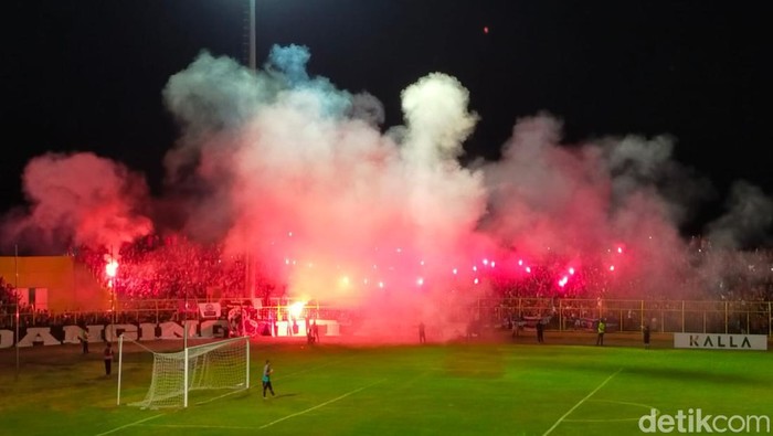 Suporter PSM Makassar menyalakan flare saat pertandingan berlangsung.