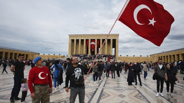 People sit at Kugulu public garden decorated with national flags and images of Turkeys founder Mustafa Kemal Ataturk, in Ankara, Turkey, Thursday, June 2, 2022. Turkey has sent a letter to the United Nations formally requesting that the country be referred to as Türkiye, the state-run news agency reported. The move is seen as part of a push by Ankara to rebrand the country and dissociate its name from the bird, turkey, and some negative connotations that are associated with it. (AP Photo/Burhan Ozbilici)