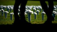 Pengunjung berjalan melewati vas berisi bunga di National Mall dekat Monumen Washington. Penembakan brutal yang meneror Amerika Serikat ini sontak membuat aturan kepemilikan senjata kembali menuai polemik.