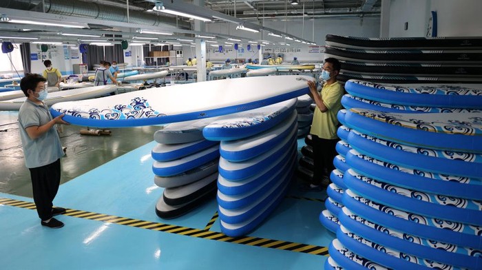 BINZHOU, CHINA - JUNE 06: An employee works on a production line for paddle boards and surfboards for overseas orders at a factory on June 6, 2022 in Binzhou, Shandong Province of China. (Photo by Chu Baorui/VCG via Getty Images)
