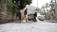 Petugas menggunakan sekop dan air bersih untuk membersihkan jalanan dari sisa-sisa abu vulkanik.
