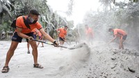 Personel penjaga pantai membersihkan jalan dari abu vulkanik di kota Juban, provinsi Sorsogon, (6/6/2022), sehari setelah letusan gunung Bulusan.