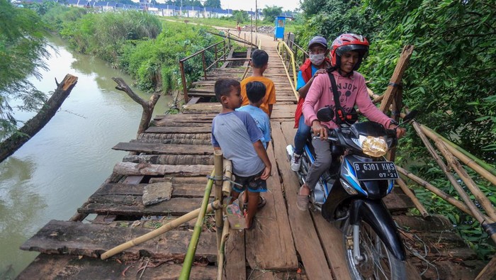 Warga melintasi akses  jembatan yang rusak penghubung antara kecamatan Jonggol dan kecamatan Klapanunggal di Singasari, Jonggol, Kabupaten Bogor, Jawa Barat, Selasa (7/6/2022).  Jembatan penghubung dua  kecamatan dan dua desa tersebut sudah rusak dan lapuk sejak tahun 2016, dan hingga saat ini belum ada perhatian dari pemerintah setempat. ANTARA FOTO/Yulius Satria Wijaya/foc.