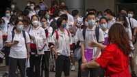Seorang relawan mengarahkan siswa yang mengenakan masker untuk memasuki sekolah pada hari pertama ujian masuk perguruan tinggi nasional Tiongkok, yang dikenal sebagai gaokao, di Beijing, Selasa, (7/6/2022).