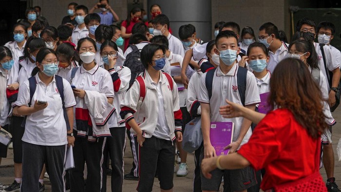 A volunteer directs students wearing face masks to enter a school for the first day of China's national college entrance examinations, known as the gaokao, in Beijing, Tuesday, June 7, 2022. More than 11 million high school students throughout China will take the annual college entrance exams which started on Tuesday after the country has just overcome severe COVID-19 outbreaks in Shanghai and Beijing, according to state media. (AP Photo/Andy Wong)