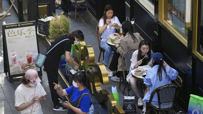 A woman takes a smartphone photo of her toasting with her friend at a reopened restaurant in a shopping mall in Beijing Monday, June 6, 2022. Diners returned to restaurants in most of Beijing for the first time in more than a month Monday as authorities further eased pandemic-related restrictions after largely eradicating a small COVID-19 outbreak in the capital under China's strict 