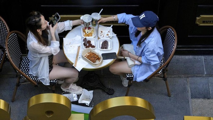 A woman takes a smartphone photo of her toasting with her friend at a reopened restaurant in a shopping mall in Beijing Monday, June 6, 2022. Diners returned to restaurants in most of Beijing for the first time in more than a month Monday as authorities further eased pandemic-related restrictions after largely eradicating a small COVID-19 outbreak in the capital under China's strict 