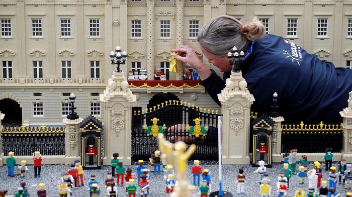 A Legoland modeller poses for a photograph while completing a model of Platinum Jubilee celebrations at Buckingham Palace, at Legoland in Windsor, Britain, May 31, 2022.  REUTERS/Peter Nicholls