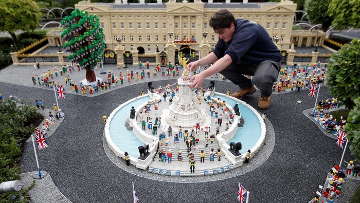 A Legoland modeller poses for a photograph while completing a model of Platinum Jubilee celebrations at Buckingham Palace, at Legoland in Windsor, Britain, May 31, 2022.  REUTERS/Peter Nicholls