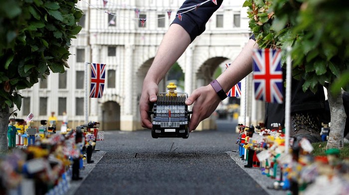 A Legoland modeller poses for a photograph while completing a model of Platinum Jubilee celebrations at Buckingham Palace, at Legoland in Windsor, Britain, May 31, 2022.  REUTERS/Peter Nicholls