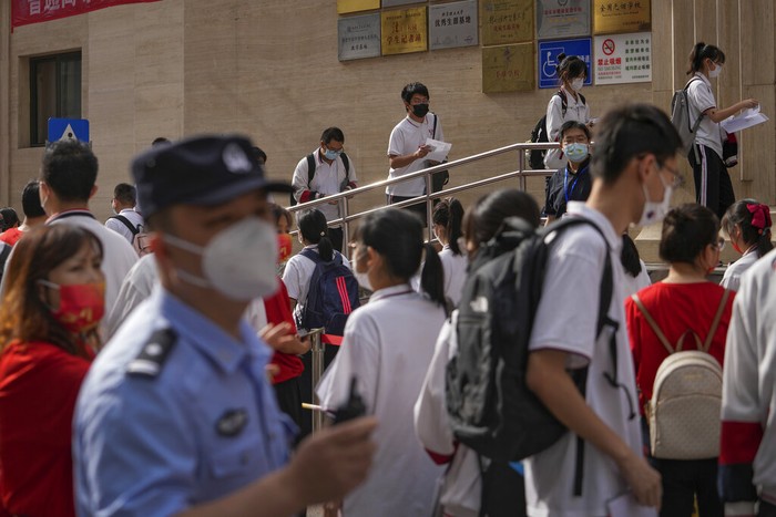 Virus Outbreak China College Entrance Exam A police officer stands watch as masked students line up to enter a school for the first day of China's national college entrance examinations, known as the gaokao, in Beijing, Tuesday, June 7, 2022. More than 11 million high school students throughout China will take the annual college entrance exams which started on Tuesday after the country has just overcome severe COVID-19 outbreaks in Shanghai and Beijing, according to state media. (AP Photo/Andy Wong)