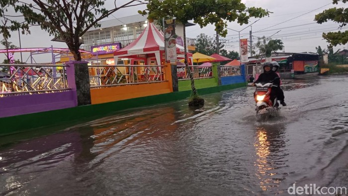Warga melintas di jalan utara Stasiun Delanggu yang tergenang air, Senin (6/6/2022) petang.