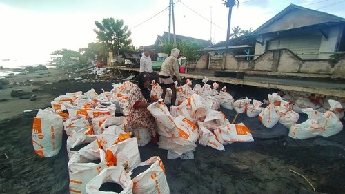 Akses jalan yang tergerus abrasi diisi dengan karung pasir, Selasa (7/6/2022)