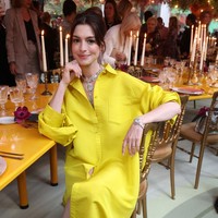 Mengenakan koleksi busana dari Bvlgari, Anne Hathaway memadukan shirt dress panjang dengan celana pendek warna kuning cerah. Foto: Getty Images