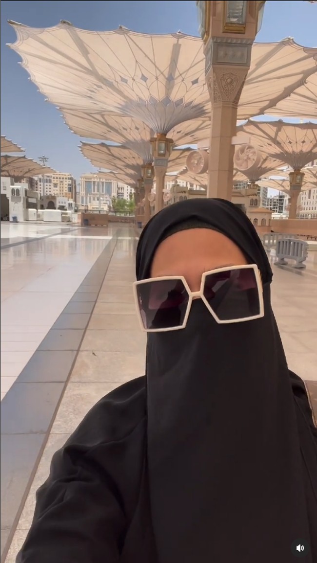 Wanita kelahiran 21 Februari 1968 itu menggunakan cadar dilengkapi dengan kacamata saat sedang berjalan di sekitar Masjid Nabawi. Menikamati jalan sendiri menuju pintu di mana shalat dhuhur akan dimulai🖤🖤🖤, tulis Donna.  Foto: Dok. Instagram @donnaharunofficial.