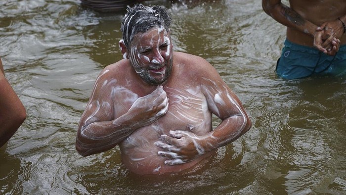 A Venezuelan migrant washes his hands on a puddle before arriving to Huixtla, Chiapas state, Mexico, Tuesday, June 7, 2022. The man is part of a larger migrant caravan, that left Tapachula on Monday, tired of waiting to normalize their status in a region with little work and still far from their ultimate goal of reaching the United States. (AP Photo/Marco Ugarte)