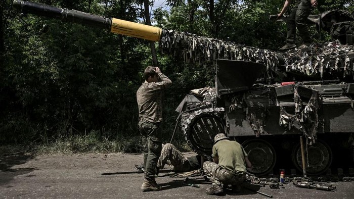 Ukrainian troop members repair an army's Main Battle Tank (MBT) in the eastern Ukrainian region of Donbas on June 7, 2022. (Photo by ARIS MESSINIS / AFP) (Photo by ARIS MESSINIS/AFP via Getty Images)
