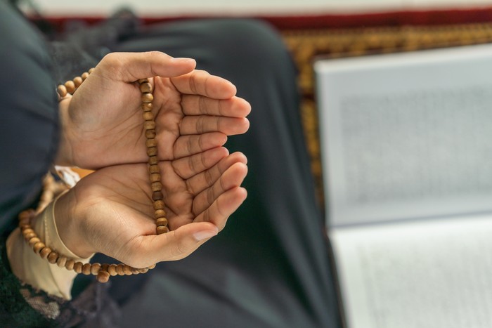 religious islamic background of hands of muslim prayer woman with prayer beads in dua praying for allah blessing in mosque