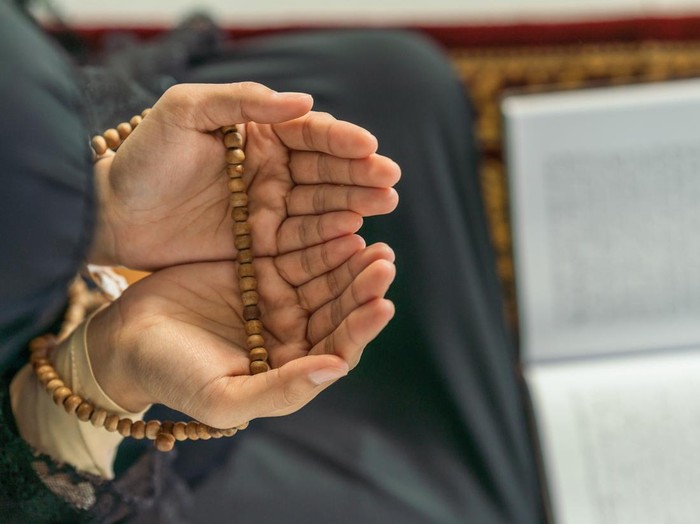 religious islamic background of hands of muslim prayer woman with prayer beads in dua praying for allah blessing in mosque