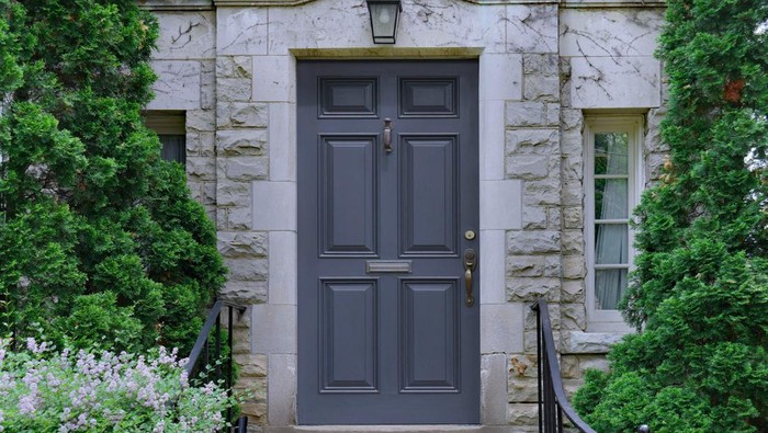 front door of stone faced house surrounded by cedar bushes