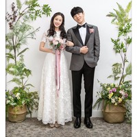 Untuk foto pre wedding, pasangan drama Korea Hi Bye Mama berpose di belakang tembok putih yang dihiasi bunga dan tanaman di sekitarnya. Kim Tae Hee memakai flatshoes nyaman yang tidak melebihi tinggi pasangannya Lee Kyu Hyung. Dia memakai gaun berbahan lace, dengan head piece yang menyerupai flower crown. Sementatara Lee Kyu Hyung memakai tuxedo bernuansa abu-abu dan hitam. Foto: dok. tvN