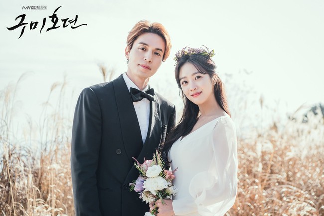 Lee Dong Wook memakai jas double breasted di hari pernikahannya dengan Jo Bo Ah. Pasangan drama Korea Tale of the Nine Tailed itu menggelar pernikahan privat dengan pemandangan gunung. Sang aktris memakai gaun berlengan panjang, dengan flower crown ungu yang serasi dengan buket bunga. Foto: dok. tvN