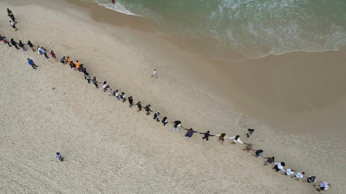 Warga Brasil Ramai-ramai Bersihkan Pantai Copacabana People create a line along Copacabana beach for a symbolic group hug with the sea on World Oceans Day in Rio de Janeiro, Brazil, Wednesday, June 8, 2022. The Route Brasil organization called for people to gather for the event coined