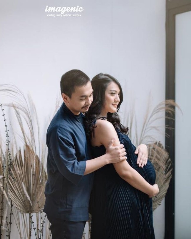 Tak melulu harus di studio foto, pemotretan maternity juga bisa dilakukan di rumah, seperti Anissa Aziza dan Raditya Dika. Dengan dekorasi berupa bunga hias dan dedaunan kering, keduanya terlihat kompak dan menawan berpose mesra sambil sama-sama mengenakan pakaian berwarna navy. Foto: Instagram
