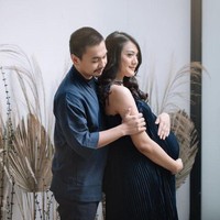 Tak melulu harus di studio foto, pemotretan maternity juga bisa dilakukan di rumah, seperti Anissa Aziza dan Raditya Dika. Dengan dekorasi berupa bunga hias dan dedaunan kering, keduanya terlihat kompak dan menawan berpose mesra sambil sama-sama mengenakan pakaian berwarna navy. Foto: Instagram