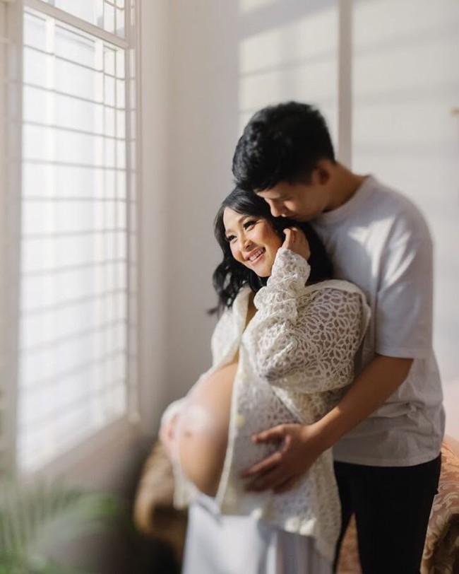 Potret maternity Rinni Wulandari bersama sang suami, Jevin Julian tampak simpel dengan kompak mengenakan pakaian berwarna putih. Keduanya terlihat berpose romantis sambil memperlihatkan baby bump di perut Rinni yang sudah cukup besar. Foto: Instagram