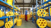 Seorang karyawan merapikan roda penggerak elevator pada rak di bengkel sebuah perusahaan di Jiangsu, China.