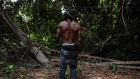 Jauh di dalam hutan di desa Ebute Ipare, Nigeria, Egbontoluwa Marigi mengukur sebatang pohon mahoni yang tinggi, lalu menebangnya dengan kapak dan parang, (24/1/2022).