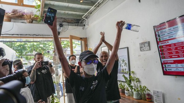 Pelanggan pertama ini merayakannya setelah membeli ganja legal di Highland Cafe, Bangkok. (Sakchai Lalit/AP)