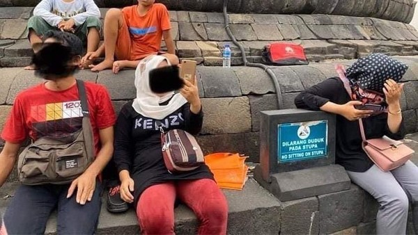 Beberapa foto pengunjung candi Borobudur viral di media sosial. Mereka terlihat asyik saja duduk di atas stupa candi. Padahal sudah ada papan larangannya, namun papan itu malah dibuat senderan tangan. (Twitter)