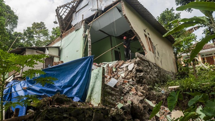 5 Rumah Hancur Akibat Tanah Bergerak di Lebak Warga berjalan melintasi rumah yang rusak akibat pergerakan tanah di Desa Cilangkap, Lebak, Banten, Sabtu (11/6/2022). Berdasarkan data BPBD Kabupaten Lebak sedikitnya lima rumah rusak dan akses jalan penghubung antardesa terputus akibat adanya bencana pergerakan tanah yang disebabkan tingginya intensitas hujan selama beberapa hari di daerah tersebut. ANTARA FOTO/Muhammad Bagus Khoirunas/foc.