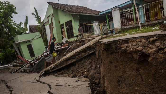 5 Rumah Hancur Akibat Tanah Bergerak di Lebak Warga berjalan melintasi rumah yang rusak akibat pergerakan tanah di Desa Cilangkap, Lebak, Banten, Sabtu (11/6/2022). Berdasarkan data BPBD Kabupaten Lebak sedikitnya lima rumah rusak dan akses jalan penghubung antardesa terputus akibat adanya bencana pergerakan tanah yang disebabkan tingginya intensitas hujan selama beberapa hari di daerah tersebut. ANTARA FOTO/Muhammad Bagus Khoirunas/foc.