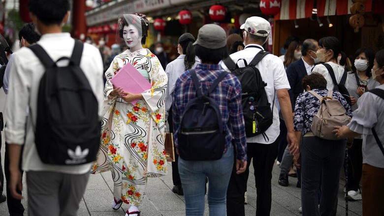 Potret Jepang yang Mulai Terima Turis Asing Foreign tourists wearing protective masks to help curb the spread of the coronavirus take a selfie at a shopping street at the Asakusa district Friday, June 10, 2022, in Tokyo. Japan on Friday eased its borders for foreign tourists and began accepting applications, but only for those on guided package tours who are willing to follow mask-wearing and other antivirus measures as the country cautiously tries to balance business and infection worries. (AP Photo/Eugene Hoshiko)