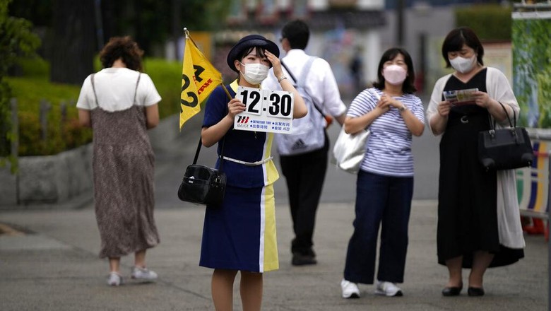Foreign tourists wearing protective masks to help curb the spread of the coronavirus take a selfie at a shopping street at the Asakusa district Friday, June 10, 2022, in Tokyo. Japan on Friday eased its borders for foreign tourists and began accepting applications, but only for those on guided package tours who are willing to follow mask-wearing and other antivirus measures as the country cautiously tries to balance business and infection worries. (AP Photo/Eugene Hoshiko)