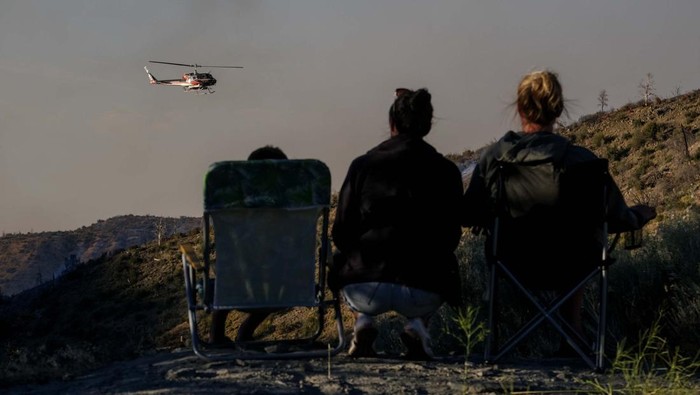 A helicopter drops water on the Sheep Fire burning in Wrightwood, Calif., Sunday, June 12, 2022. (AP Photo/Ringo H.W. Chiu)