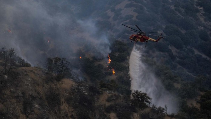 A helicopter drops water on the Sheep Fire burning in Wrightwood, Calif., Sunday, June 12, 2022. (AP Photo/Ringo H.W. Chiu)