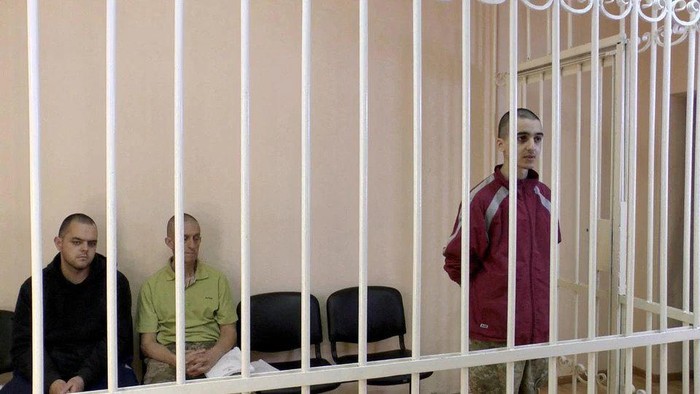 FILE PHOTO: A still image, taken from footage of the Supreme Court of the self-proclaimed Donetsk Peoples Republic, shows Britons Aiden Aslin, Shaun Pinner and Moroccan Brahim Saadoun captured by Russian forces during a military conflict in Ukraine, in a courtroom cage at a location given as Donetsk, Ukraine, in a still image from a video released June 8, 2022. Video taken June 8, 2022. (Supreme Court of Donetsk Peoples Republic/Handout via REUTERS TV/File Photo)