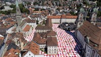Kain piknik raksasa menutupi jalan-jalan dan alun-alun Klosterhof selama instalasi seni BIGNIK yang diprakarsai oleh seniman konsep Swiss Frank dan Patrik Riklin di kota tua St. Gallen, Swiss, Minggu, (12/6/2022).