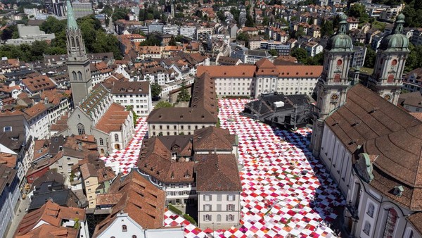 Kain piknik raksasa menutupi jalan-jalan dan alun-alun Klosterhof selama instalasi seni BIGNIK yang diprakarsai oleh seniman konsep Swiss Frank dan Patrik Riklin di kota tua St. Gallen, Swiss, Minggu, (12/6/2022).