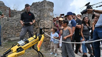 Pengunjung melihat Spot, robot berkaki empat di Taman Arkeologi Pompeii, dekat Napoli, Italia selatan.